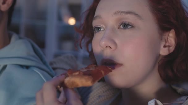 Zbliżenie Młodej Rudowłosej Białej Kobiety Jedzącej Pizzę Oglądającej Nocy Niewidzialną — Wideo stockowe