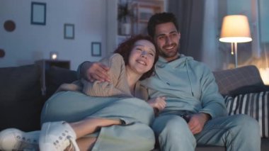 Çoklu etnik çeşitlilikte romantik partnerlerin, geceleri kanepede kıvrılıp, görünmez TV izlerken, kahkahalar atarken, Kafkasyalı bir kızın melez erkek arkadaşına yaslandığı düzenli bir çekim.