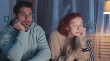 Orta ölçekli, sıkılmış ve yorgun bir adam ve beyaz bir kadın oturma odasında oturuyor, görünmez TV kanallarını değiştiriyor, sonra onu kapatıyor, ayağa kalkıyor ve uzaklaşıyor.