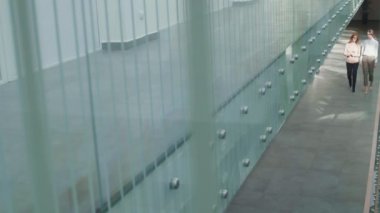 Beyaz kadın iş kadınlarının şık ofis kıyafetleri giyip iş merkezinin koridorunda sohbet ettikleri yüksek açılı bir manzara.