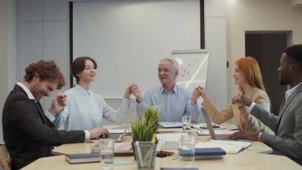 会議中に5人の多様なビジネス同僚が机の上に座り 手を取り合い エアパンチを作りました — ストック動画