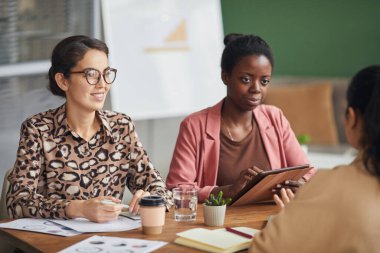 Toplantı masasında otururken projeyi tartışan çok ırklı tüm kadın iş adamlarının portresi.