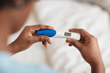 Hamilelik testini elinde tutan genç Afro-Amerikalı kadının yüksek açılı görüntüsü.