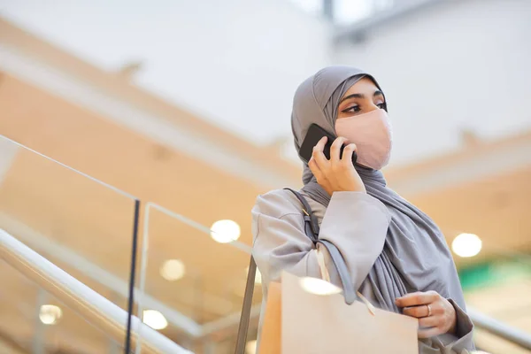 在商场的自动扶梯上 现代中东女性头戴面具 用智能手机说话的肖像 复制空间 — 图库照片