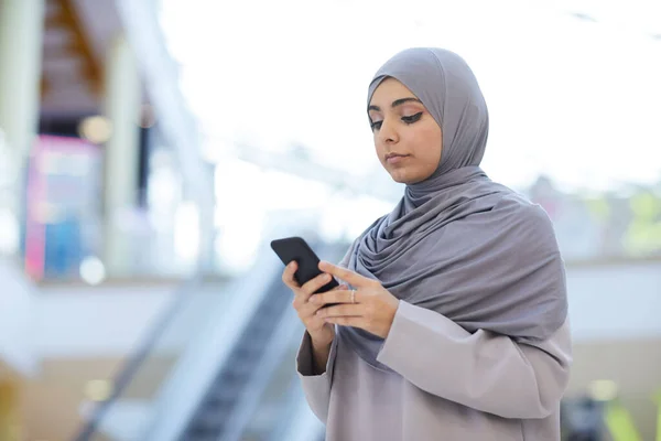站在购物中心时 举起现代中东女人头戴头巾 用智能手机的肖像 复制空间 — 图库照片