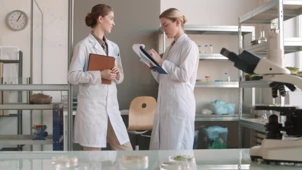 两名女科学家身穿医疗服 站在实验室里 用现代设备进行交流和报告 被查封 — 图库视频影像