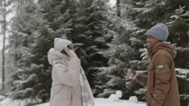 Genç melez bir kadının kış ormanlarında yürürken genç Afrikalı bir adama beşlik çaktığı orta boy bir fotoğraf. Sonra sarılıyorlar.