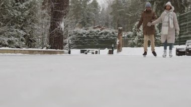 Genç Afro-Amerikalı adam ve güzel melez kız arkadaşının parkta paten yapıp el ele tutuşması.