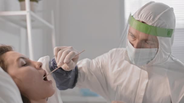 Närbild Läkare Som Bär Skyddsdräkt Och Ansiktsskydd Tar Salivprov Med — Stockvideo