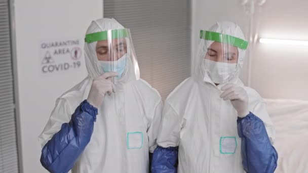 两名白种人实验室工作人员穿着白色的防护服 摘下护目镜和面罩 相互望着对方 在漫长的一天后呼呼大睡 组成了一个高角形的中型实验室 — 图库视频影像