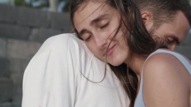 Siyah saçlı, beyaz saçlı, gülümseyen, beyaz tişörtlü genç erkek arkadaşına sarılan güzel bir kız.