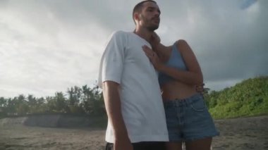 Kafkasyalı romantik kadın ve erkeğin güneşli bir günde tropikal adanın sahilinde durduğu, sonra yürüdüğü ve köpeklerinin etrafta koştuğu bir sahne.