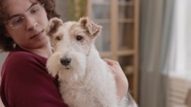 Orta sınıf, sevimli Fox Terrier köpeği. Beyaz, sevecen bir erkek sahibinin kollarında nazik gözleri var. Kahverengi gözlü adam evcil hayvanı öpüyor.