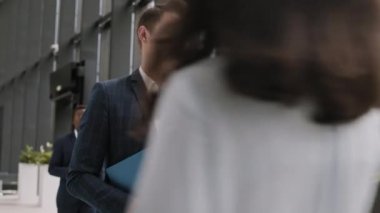 Mavi kareli takım elbiseli genç beyaz iş adamının ofis koridorunda iş arkadaşıyla telefon görüşmesi yaparken orta boy bir fotoğrafı.
