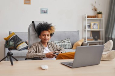 Evde ve internet üzerinden video oyunu oynayan gülümseyen Afro-Amerikan çocuk portresi, genç oyuncu veya blog yazarı konsepti, kopyalama alanı