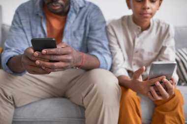 Tanımlanamayan Afrikalı Amerikalı bir adamın oğluyla koltukta oturup akıllı telefonlardan bir şeyler izlediği kavramsal bir fotoğraf.