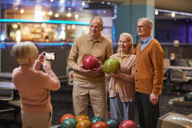 Bir grup son sınıf öğrencisi bowling oynarken fotoğraf çekiyor ve bowling salonunda eğleniyor.