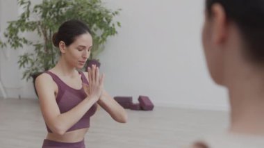 Genç, güzel, beyaz bir kadının yoga minderinde oturması yoga antrenmanını bitirmesi ve önünde oturan tanınmamış kadın koça teşekkür etmesi.