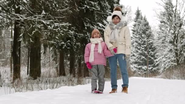 陽気なアジアの母親と子供のフルショットのPovは パフジャケットを着て ポンポンとスカーフを手に帽子 目を見て その後 カメラで 雪の冬の公園でポーズ — ストック動画