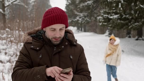 Kış Karlı Parkında Dikilip Akıllı Telefona Bakan Neşeli Beyaz Adamın — Stok video