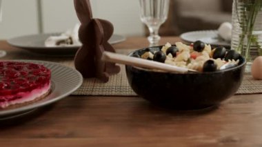 Lezzetli yemek masasının izini sürüyorum. Meyveli pasta, salata, zeytin, peynir, sebze, renkli yumurta, Paskalya 'da çikolatalı tavşan.