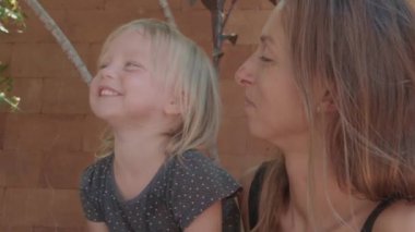 Genç, mutlu, beyaz bir kadının masada oturup tatlı kızıyla eğlenmesine yakından bakın.