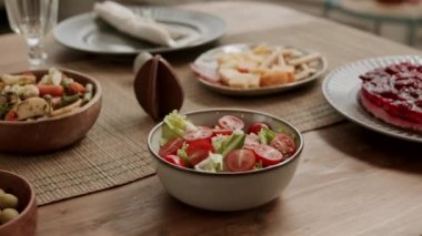 Çilekli pasta, salata, zeytin, peynir, sebze, renkli yumurta, Paskalya 'da çikolatalı tavşan gibi pek çok lezzetli yemekle süslenmiş bayram yemeğinin solunda.