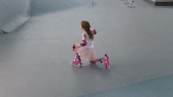 Zoom In十代の白人の女の子身に着けています安全肘と膝パッド学習ローラースケートで屋内スケートセンター — ストック動画