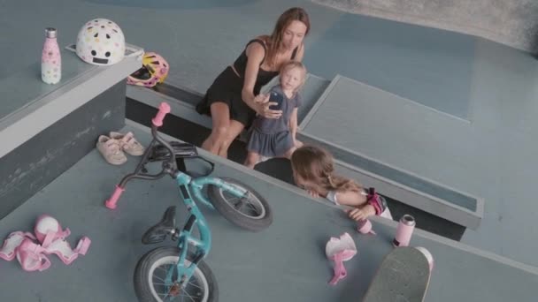 Paten Kayan Genç Kız Onlara Katılırken Kaykay Pistindeki Rampada Oturan — Stok video