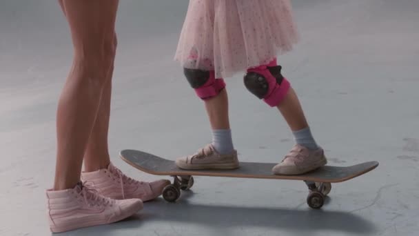 一名无法辨认的女子的下半身中照 教她那难以辨认的女儿如何穿着五颜六色的安全膝和肘板滑板 — 图库视频影像