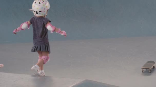 身穿长统袜的瘦弱女子和身穿安全衣的白发小女孩在室内滑板场滑板时难以辨认 — 图库视频影像