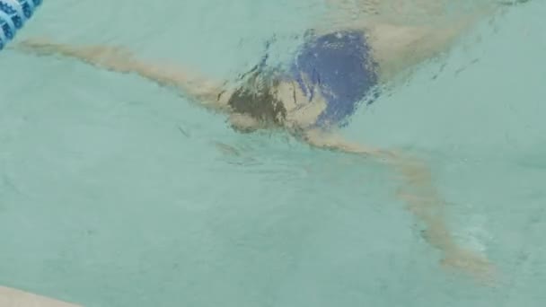 身穿蓝色游泳衣的年轻貌美的白人女子从游泳池中浮出水面 在游泳池边休息的高视角图像 — 图库视频影像