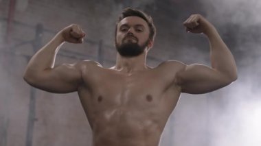 Eğitimden sonra spor salonunda kameraya bakan çıplak vücutlu yakışıklı bir sporcunun düşük açılı portresi.