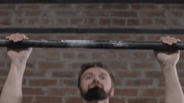 Kafkas sakallı sporcunun spor salonundaki yatay barda spor yaparken gri tişört giymesini yakın çekim.