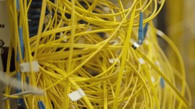 Close up of tangle of yellow wires in server room with no people