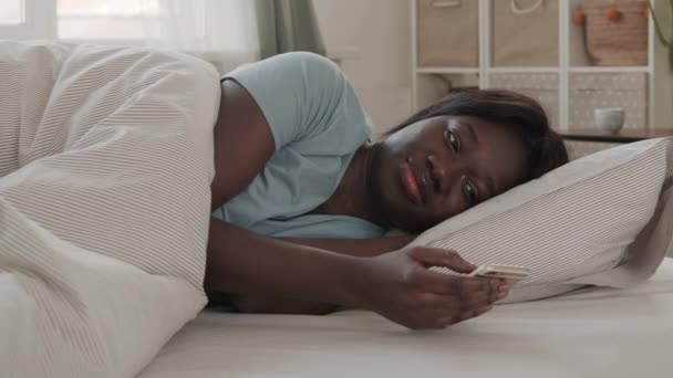 Mavi Pijama Giyen Genç Afrikalı Bir Kadının Yatakta Yatıp Telefonuyla — Stok video