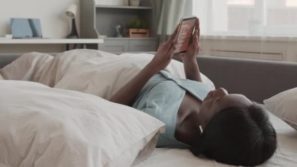 Блокировка Молодой Африканской Женщины Пижаме Беспроводных Наушниках Лежащих Постели Дома — стоковое видео