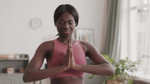 将身穿粉色上衣的年轻非洲裔美国女运动员关在客厅里 闭着眼睛练习瑜伽 — 图库视频影像