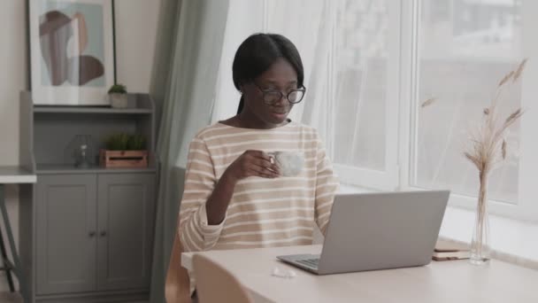 Średnie Ujęcie Młodej Afrykańskiej Freelancerki Ubraniach Okularach Siedzącej Przy Biurku — Wideo stockowe