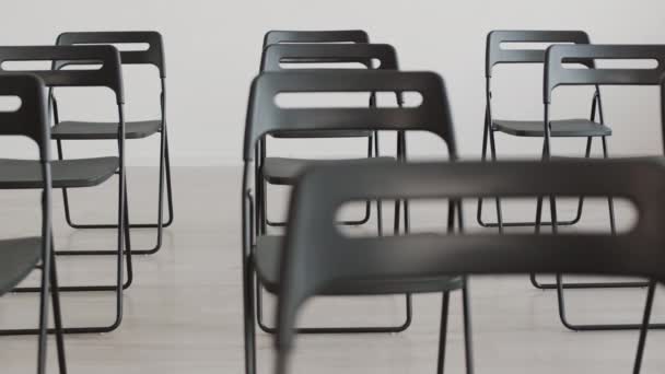 ラックフォーカス昼間のイベントのための会議室に設置された黒い折りたたみ椅子のSteadicam — ストック動画