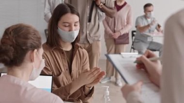 Hastanedeki çok ırklı hastaların el dezenfektanı kullanarak masa başında oturması, tanınamaz bir sağlık çalışanı olması, vücut ısılarını temassız termometreyle ölçmesi.