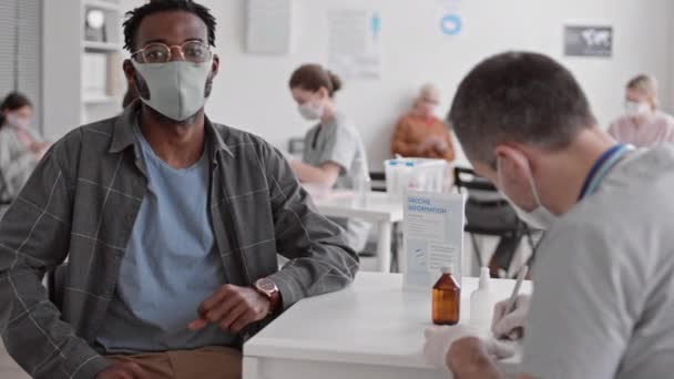 Punto Vista Medio Joven Africano Con Gafas Mascarilla Sentado Escritorio — Vídeos de Stock