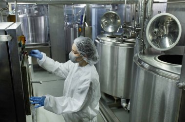 Temiz gıda fabrikasında çalışan genç kadın işçi işletim makinelerinin yüksek açılı görüntüsü, boşluğu kopyala