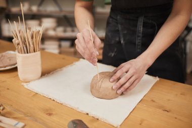 Çömlekçilik atölyesinde seramik kâse dekore eden tanınmayan genç adamın sıcak tonlarında.