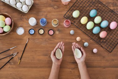 Çocuk işçilerin arka planında pastel renkli Paskalya yumurtalarını ahşap masanın üzerine boyamak, DIY Paskalya süslemeleri, kopyalama alanı