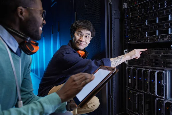 Portrait of two young technicians setting up server network while working in data center, copy space