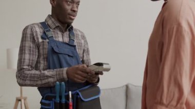 Akıllı telefon ve NFC teknolojisi kullanarak zanaatkâra para ödeyen Afro-Amerikalı genç bir kadın.