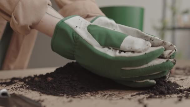 Zbliżenie Nierozpoznawalnej Osoby Noszącej Rękawice Ogrodnicze Zbierającej Glebę Powierzchni Stołu — Wideo stockowe