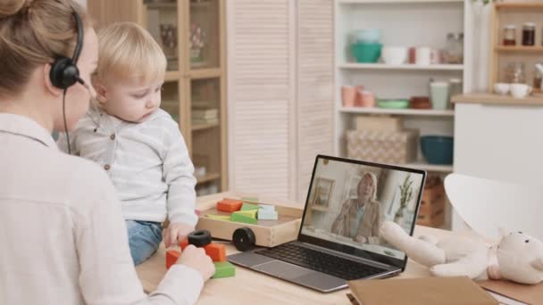 집에서 일하는 어머니의 너머로 컴퓨터 상에서 상사와 온라인 회의를 아기가 — 비디오