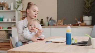 Evde masa başında oturan, iki yaşındaki sinir bozucu oğlunu kollarında tutan yorgun, beyaz kadın ebeveynin zamanı. Kadın deftere yazarken, çocuk ağlarken ve kaçmaya çalışırken.